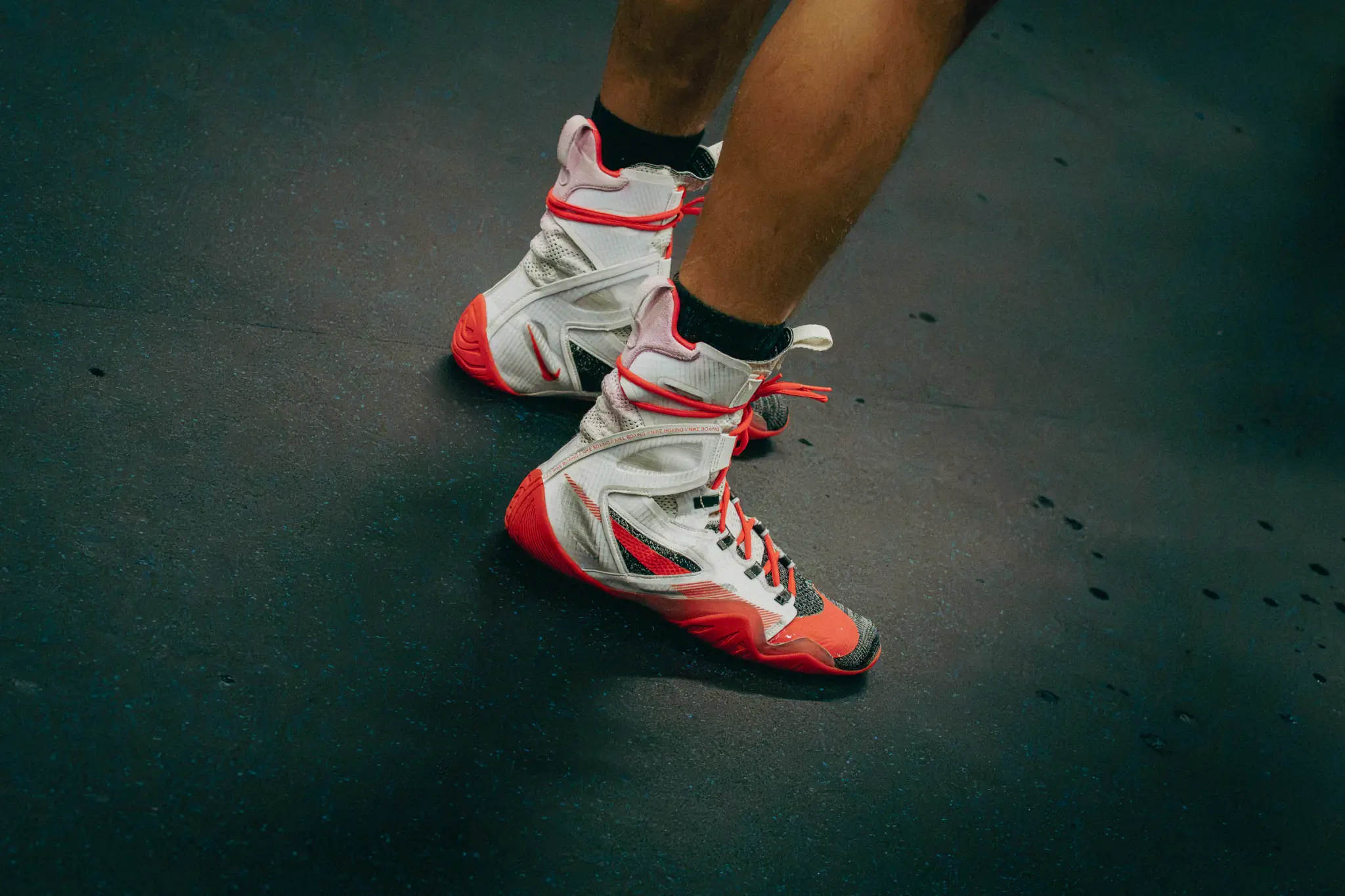 Rot-weisse Boxschuhe in Bewegung auf der dunklen Trainingsmatte.